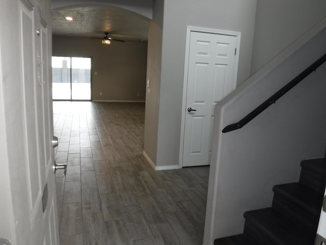 interior space with baseboards, a ceiling fan, wood finished floors, and arched walkways