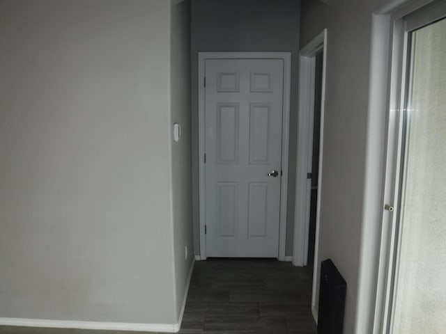 hall featuring baseboards and dark wood-type flooring