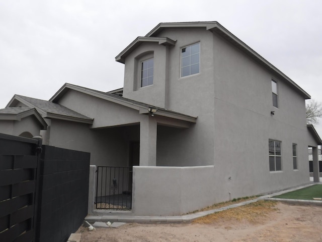 view of property exterior with fence private yard, a gate, and stucco siding