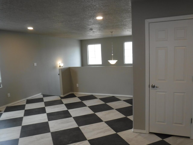 empty room with light floors, baseboards, a textured ceiling, and recessed lighting
