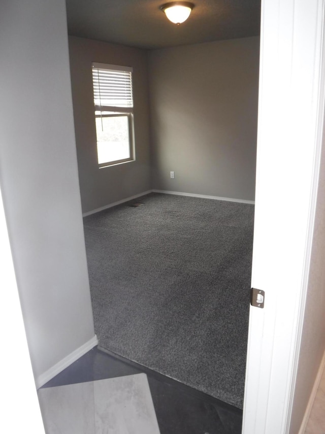 empty room with dark carpet and baseboards