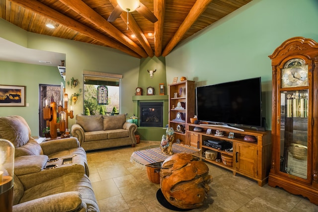 living room with a glass covered fireplace, a ceiling fan, wooden ceiling, and beam ceiling