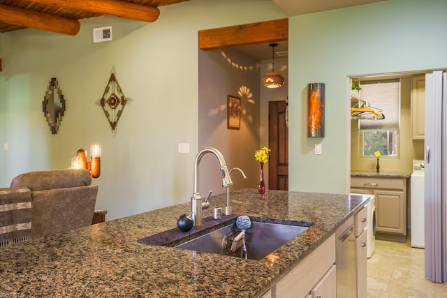 kitchen with washer / clothes dryer, visible vents, beamed ceiling, dark stone counters, and a sink