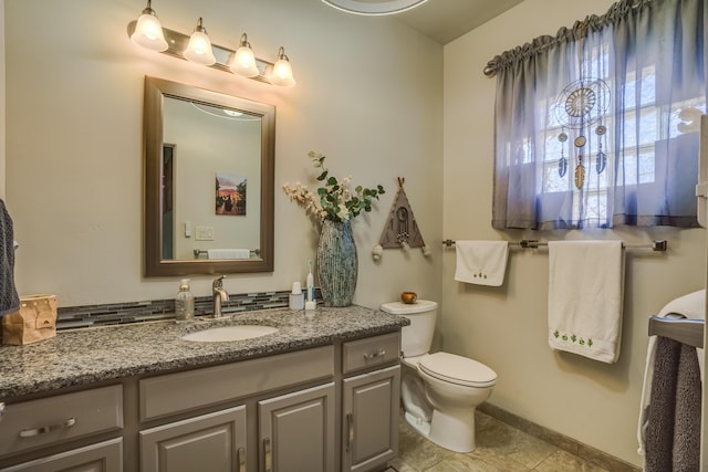 bathroom with tile patterned floors, vanity, baseboards, and toilet