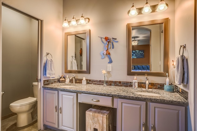 bathroom featuring double vanity, a sink, and toilet
