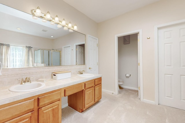 4104 Killington Rd NW, Albuquerque, NM 87114 - full bathroom with double vanity, a shower stall, toilet, decorative backsplash, and baseboards