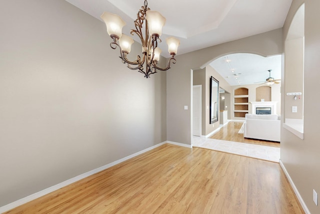 4104 Killington Rd NW, Albuquerque, NM 87114 - unfurnished room featuring arched walkways, built in features, ceiling fan, a glass covered fireplace, and light wood finished floors