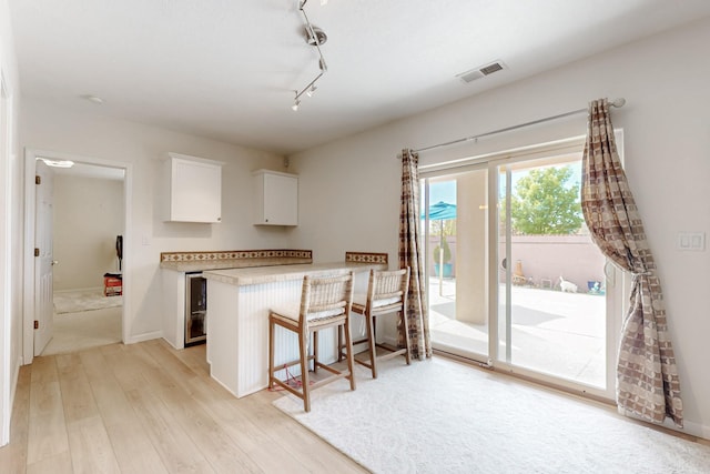 4104 Killington Rd NW, Albuquerque, NM 87114 - kitchen featuring white cabinets, light wood-type flooring, light countertops, a breakfast bar, and track lighting