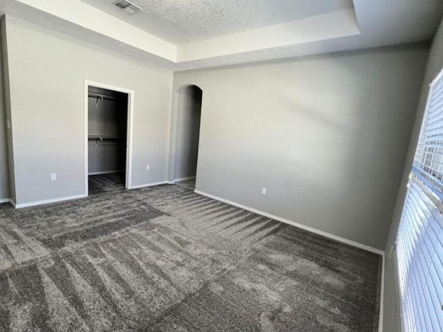 6016 N Sandia Ct, Rio Rancho, NM 87144 - unfurnished bedroom featuring a raised ceiling, carpet floors, arched walkways, baseboards, and a textured ceiling