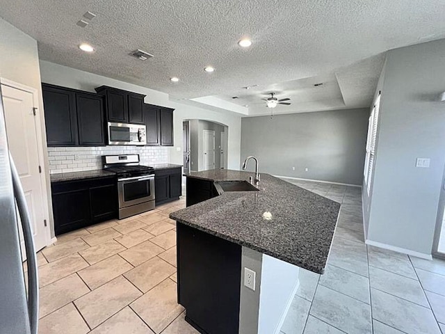 6016 N Sandia Ct, Rio Rancho, NM 87144 - kitchen featuring appliances with stainless steel finishes, a sink, dark cabinets, a ceiling fan, and arched walkways