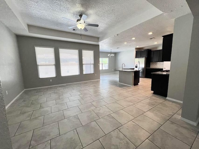 6016 N Sandia Ct, Rio Rancho, NM 87144 - kitchen with open floor plan, a tray ceiling, a textured ceiling, stainless steel fridge with ice dispenser, and dark cabinetry