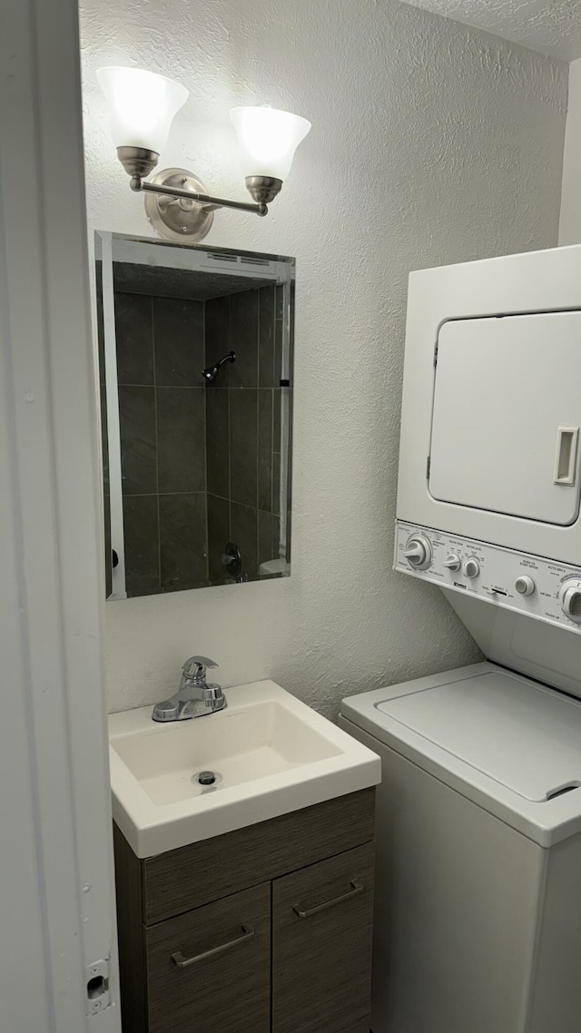 3839 Montgomery Blvd NE Unit 724, Albuquerque, NM 87109 - full bathroom with vanity, stacked washer and dryer, a textured wall, and walk in shower