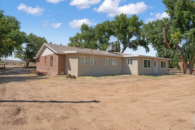 rear view of property featuring stucco siding and brick siding