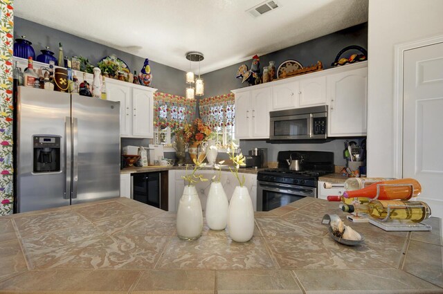 4844 Stafford Pl NW, Albuquerque, NM 87120 - kitchen featuring visible vents, wine cooler, stainless steel appliances, white cabinetry, and tile countertops