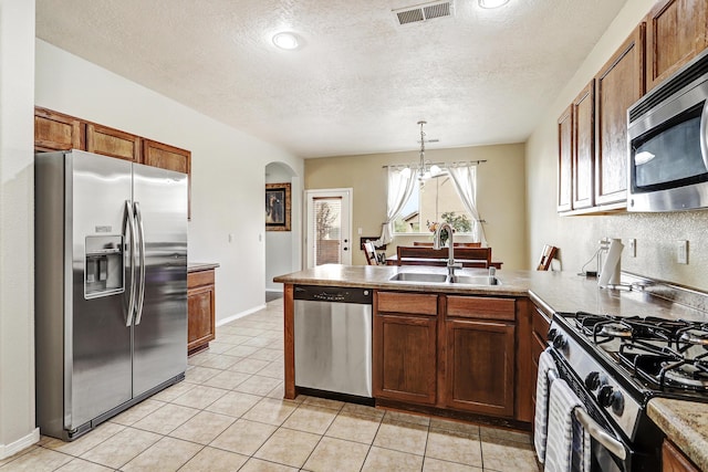 2467 Corvara Dr SE, Rio Rancho, NM 87124 - kitchen with appliances with stainless steel finishes, a sink, a peninsula, arched walkways, and decorative light fixtures