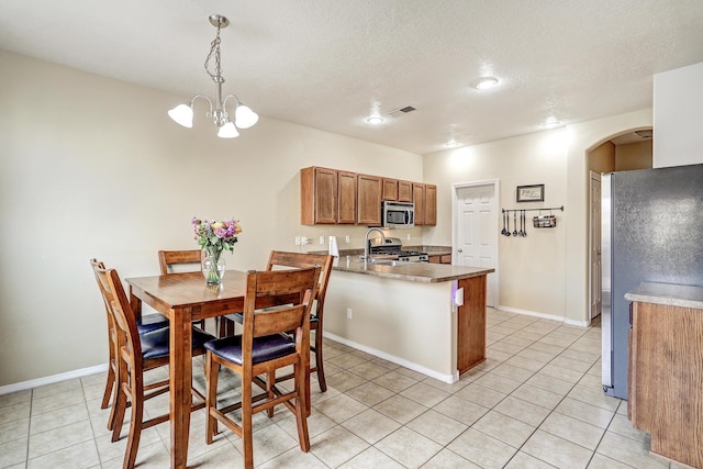 2467 Corvara Dr SE, Rio Rancho, NM 87124 - dining room featuring arched walkways, light tile patterned flooring, a chandelier, baseboards, and a textured ceiling