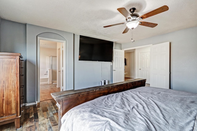 2467 Corvara Dr SE, Rio Rancho, NM 87124 - bedroom featuring hardwood / wood-style floors, a ceiling fan, baseboards, ensuite bath, and a textured ceiling