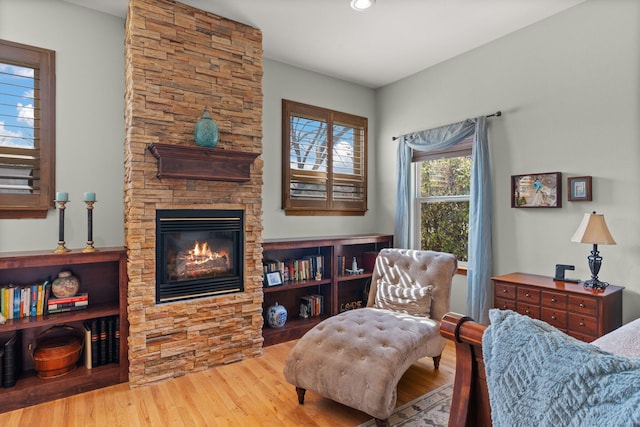 sitting room featuring a stone fireplace, recessed lighting, and wood finished floors