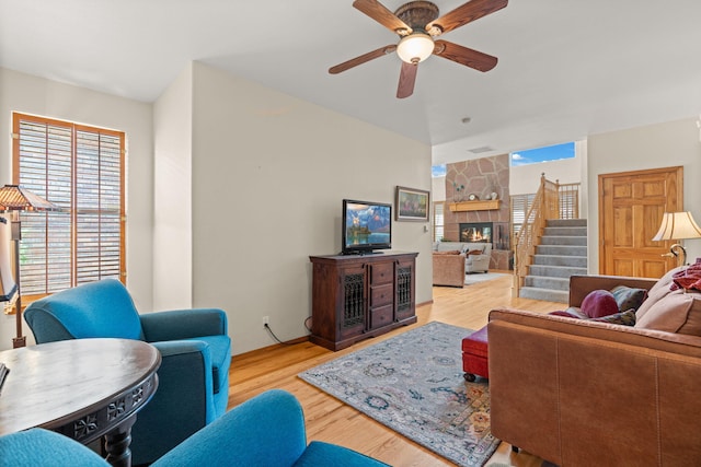 living room with visible vents, a stone fireplace, a ceiling fan, and wood finished floors