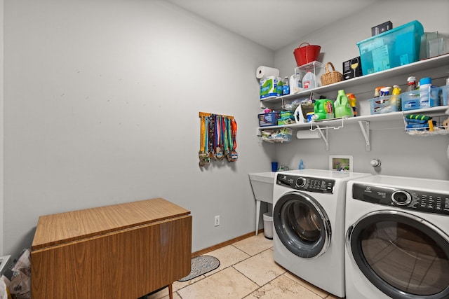 washroom featuring laundry area, baseboards, and washer and clothes dryer