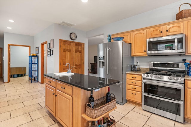 kitchen featuring visible vents, a sink, appliances with stainless steel finishes, an island with sink, and recessed lighting
