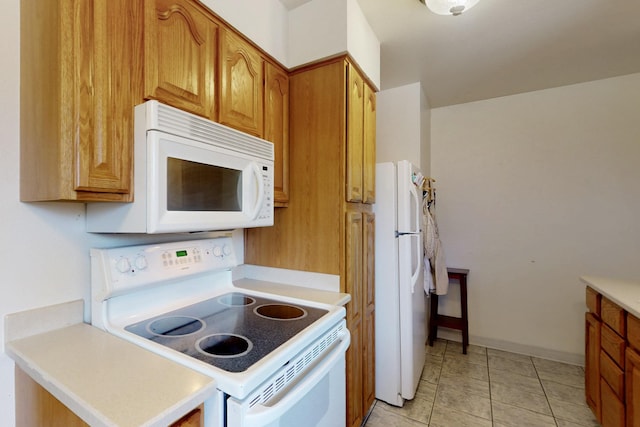 kitchen featuring light countertops, light tile patterned flooring, brown cabinetry, and white appliances
