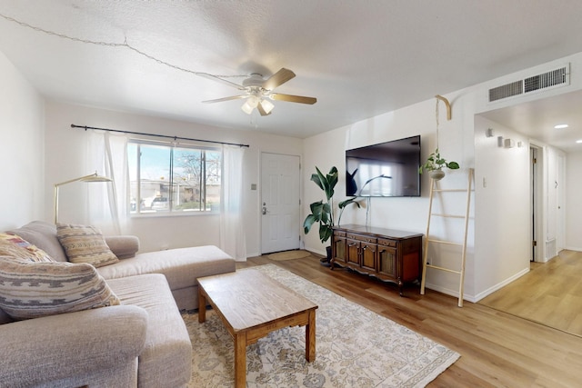 living area with ceiling fan, baseboards, light wood finished floors, and visible vents