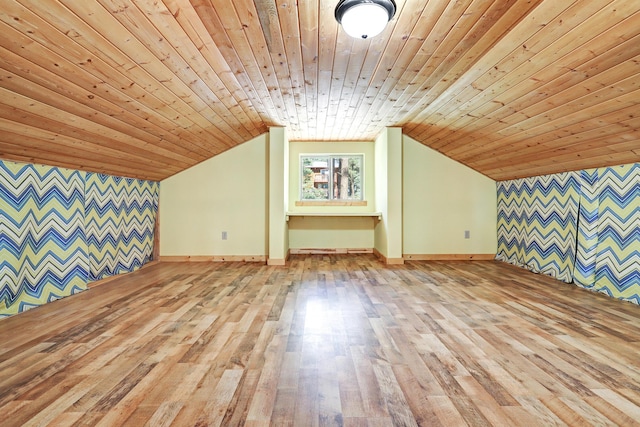 additional living space with lofted ceiling, baseboards, an accent wall, wood ceiling, and wood finished floors