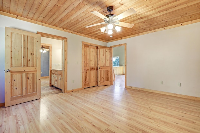 unfurnished bedroom featuring light wood finished floors, baseboards, ceiling fan, ensuite bath, and wood ceiling