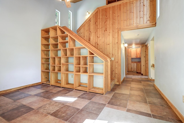 stairway featuring a towering ceiling, stone finish floor, and baseboards