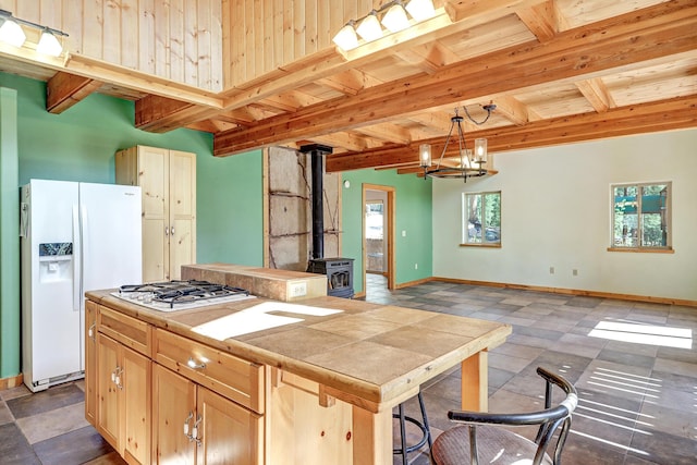 kitchen featuring beamed ceiling, white appliances, tile countertops, a wood stove, and wooden ceiling
