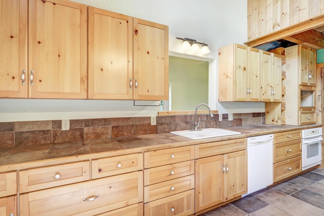 kitchen featuring tile counters, white appliances, a sink, and light brown cabinets