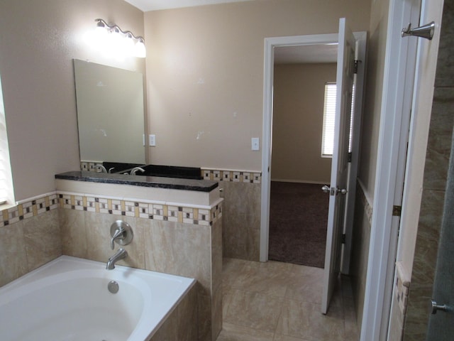 full bathroom with a garden tub, tile patterned flooring, and tile walls