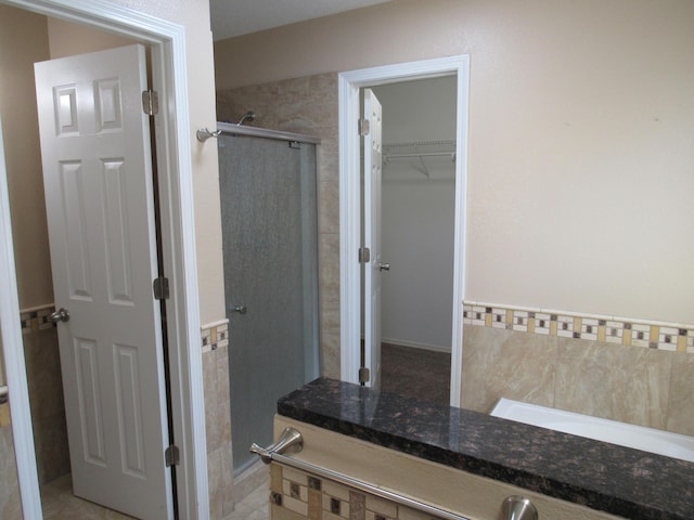 bathroom with a spacious closet and a stall shower
