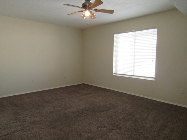 unfurnished room with baseboards, dark colored carpet, and ceiling fan
