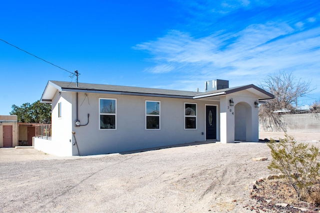 ranch-style house featuring stucco siding and fence