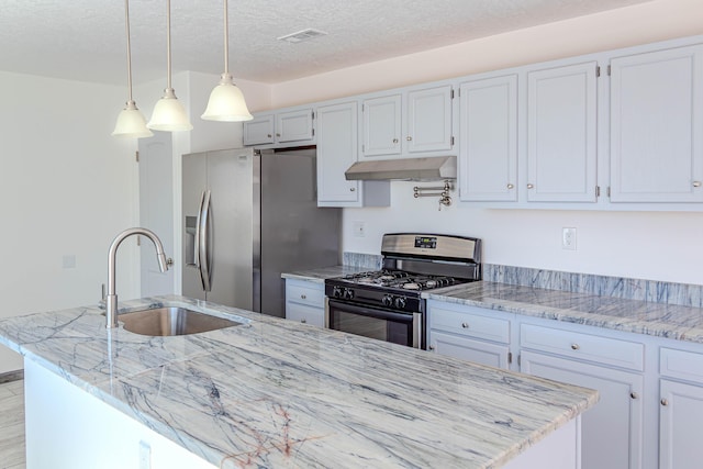 kitchen featuring range with gas stovetop, a textured ceiling, a sink, under cabinet range hood, and stainless steel fridge