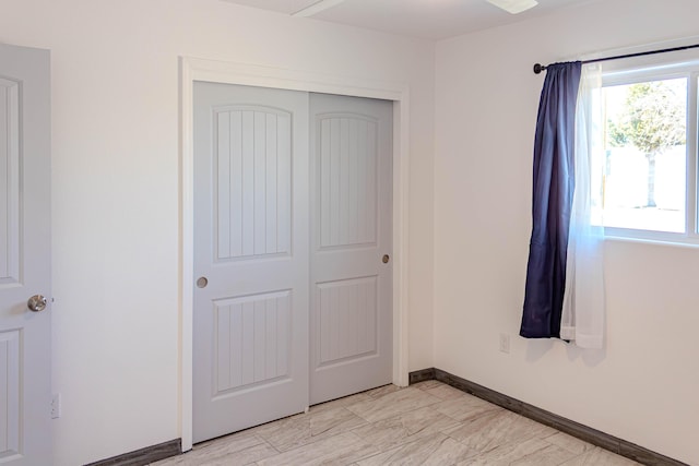 unfurnished bedroom featuring baseboards, marble finish floor, and a closet