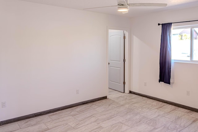 unfurnished room featuring ceiling fan and baseboards