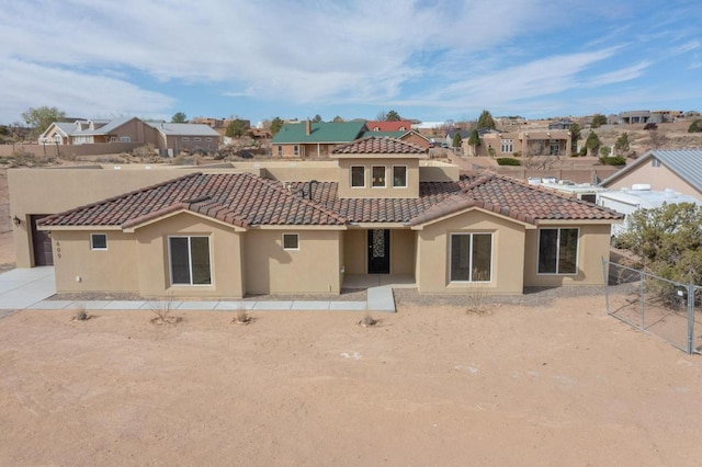 rear view of house with stucco siding, fence, a residential view, and a tile roof