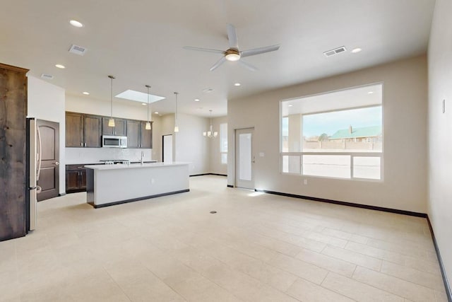 kitchen featuring stainless steel microwave, visible vents, light countertops, open floor plan, and a ceiling fan