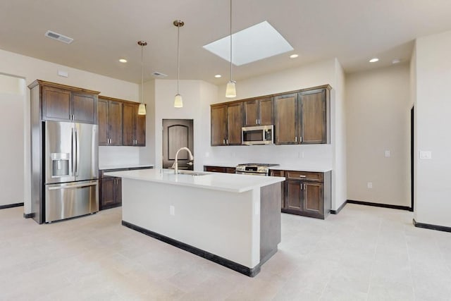 kitchen with a sink, dark brown cabinetry, light countertops, a skylight, and appliances with stainless steel finishes