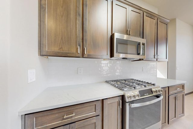 kitchen featuring backsplash, light stone countertops, and appliances with stainless steel finishes