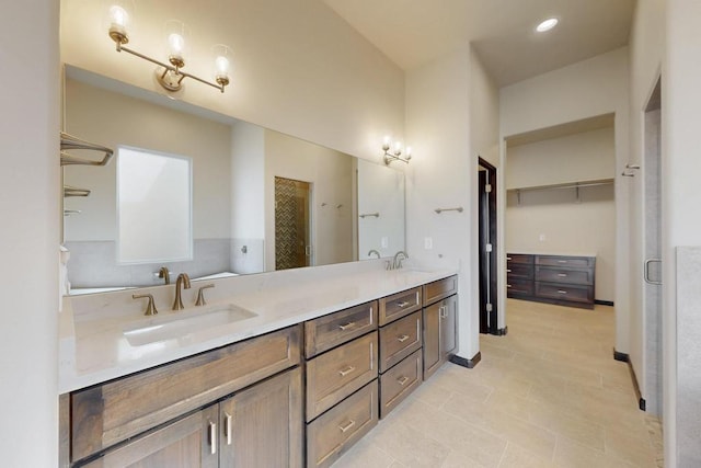 full bath with double vanity, a spacious closet, and a sink