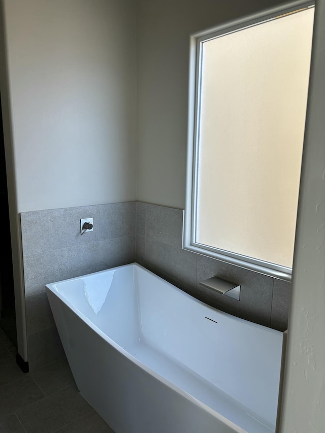 full bath featuring tile walls, a freestanding bath, a wainscoted wall, and tile patterned floors