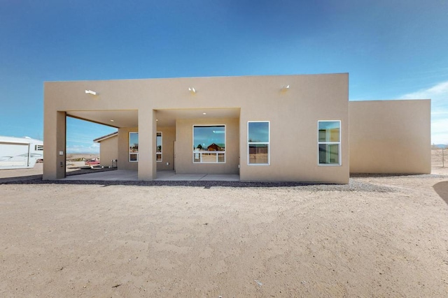 back of property with a patio and stucco siding