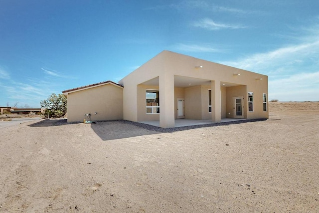 rear view of property with stucco siding and a patio area