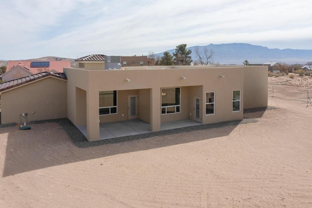 back of property featuring stucco siding, a patio, and a mountain view