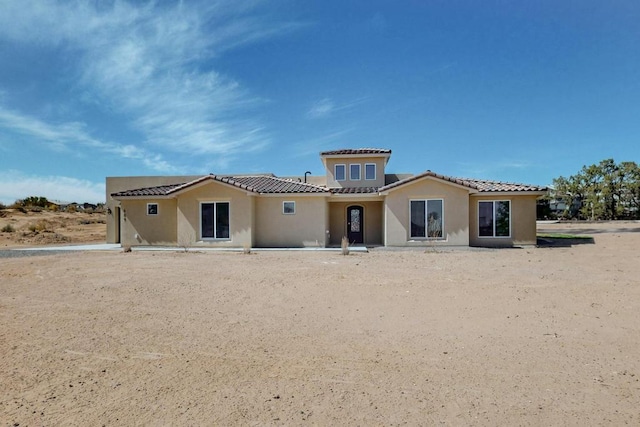 rear view of property with stucco siding and a tiled roof