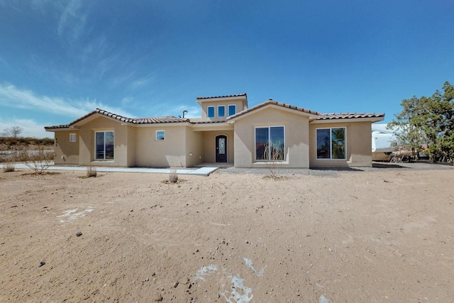 back of property with stucco siding and a tiled roof